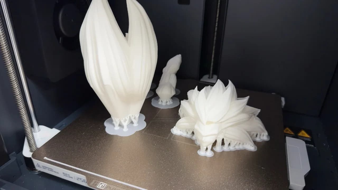 White sculptural parts printing with supports on a 3D printer bed