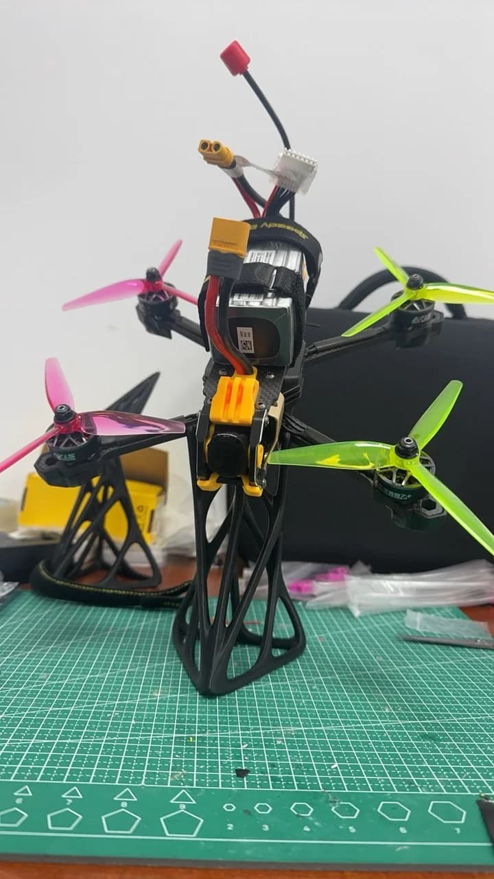 Completed FPV drone standing vertically with bright propellers and battery attached