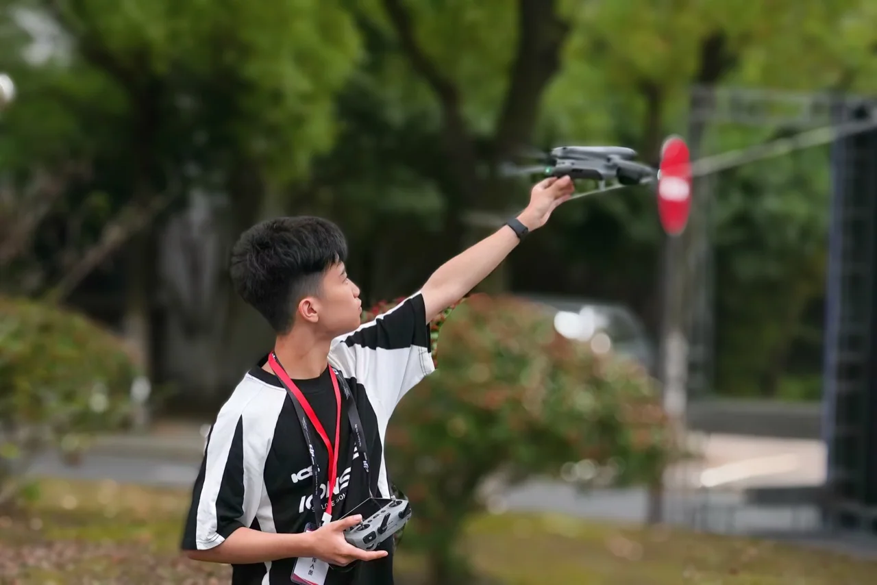 Byron launches a compact camera drone outdoors while holding its controller