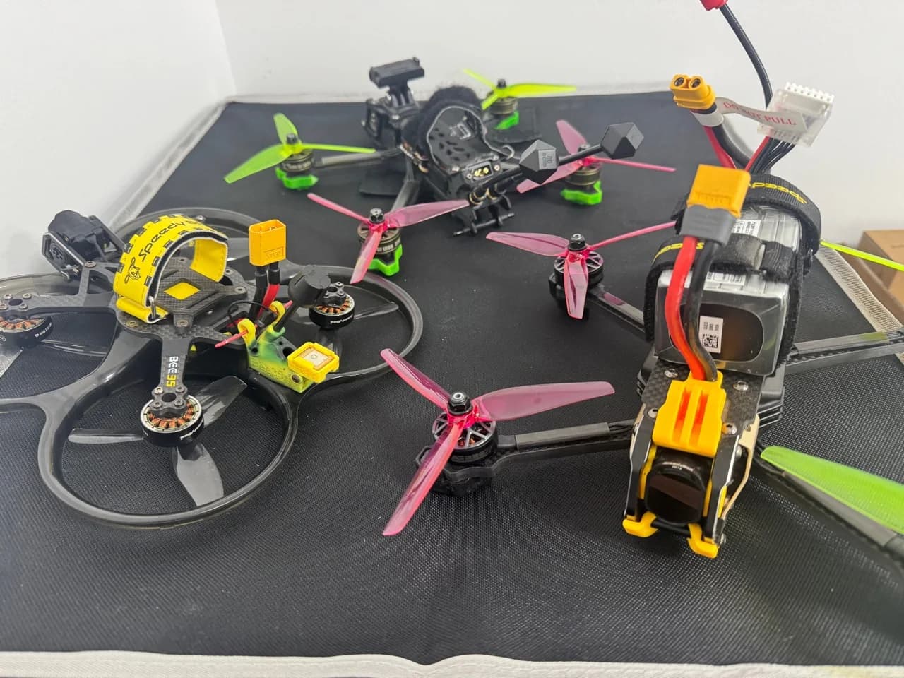Several custom FPV drones arranged together with different frames, propellers and camera mounts