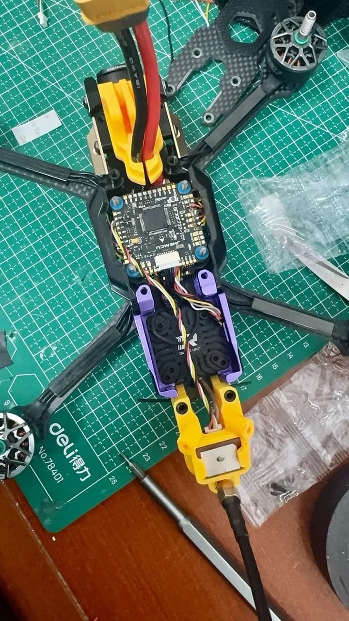 FPV drone frame opened on a cutting mat with the flight controller and wiring exposed
